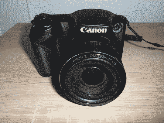 Front facing picture of the camera. Its lens is way bigger and it also has a more ergonomic design